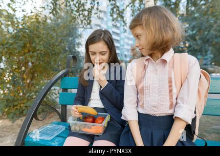 Outdoor Portrait von Grundschüler mit Lunch Boxen, gesunde Schule Frühstück. Kinder essen, reden, lachen. Stockfoto