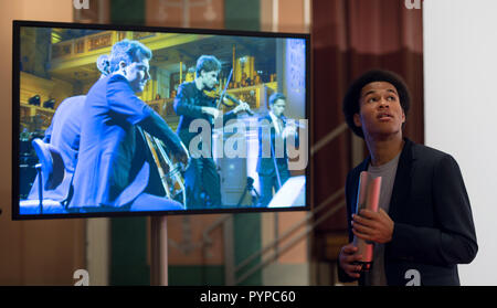 Berlin, Deutschland. 14 Okt, 2018. Sheku KANNEH - Maurer (nach - Wachstum Künstler des Jahres, Cello) mit dem OPUS KLASSIK Trophée steht auf dem TV-Bildschirm mit den Musikern von 4 TimesBaroque. Preisverleihung des Opus-Klassik 2018 durch den Verein zur Förderung der Klassischen Musik eV im Konzerthaus Berlin am 14.10.2018. | Verwendung der weltweiten Kredit: dpa/Alamy leben Nachrichten Stockfoto