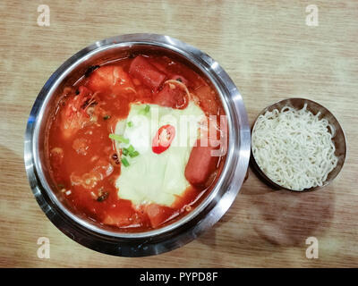 Leckeres koreanisches Essen Yukgaejang spicy Seafood Suppe mit Käse, Yukgaejang Hot Pot ist Koreanisch Eintopf mit Kimchi, Nudeln, Käse, Schinken, Wurst, mu Stockfoto