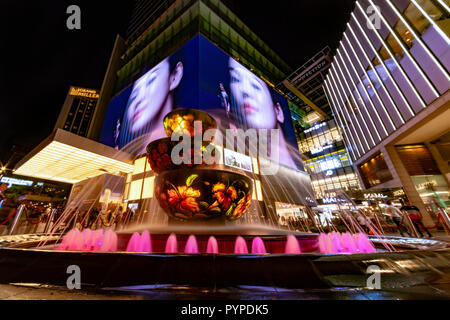 KUALA LUMPUR, 16. August 2018 - Bunte Brunnen vor der beschäftigt und überfüllten 'Pavilion' Einkaufszentrum der Stadt bei Nacht Stockfoto