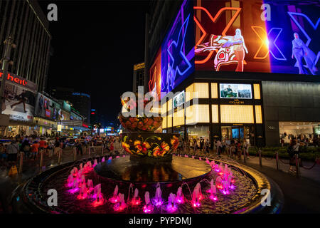 KUALA LUMPUR, 16. August 2018 - Bunte Brunnen vor der beschäftigt und überfüllten 'Pavilion' Einkaufszentrum der Stadt bei Nacht Stockfoto