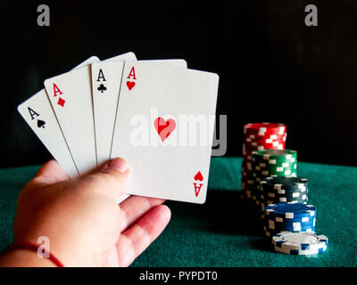 Eine Person spielen Poker mit den vier Asse der ein Deck in der Hand und poker chips in verschiedenen Farben auf der grünen Matte Stockfoto