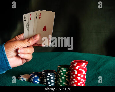 Eine Person spielen Poker mit den vier Asse der ein Deck in der Hand und poker chips in verschiedenen Farben auf der grünen Matte Stockfoto