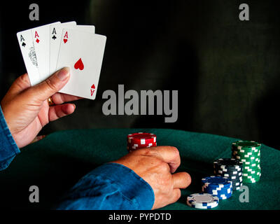 Eine Person spielen Poker mit den vier Asse der ein Deck in der Hand und poker chips in verschiedenen Farben auf der grünen Matte Stockfoto