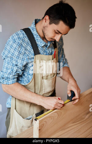 Hand eines Zimmermanns, die Messung einer Holzbohle Stockfoto
