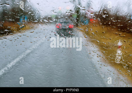 Regen auf Glas, fahren Sie auf der Autobahn im schweren Regen, Regentropfen auf dem Auto Glas, nassem Asphalt Stockfoto