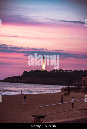 Biarritz, Frankreich. Die Menschen genießen den Sommer Sonnenuntergang am Strand namens Grand Plage. Leuchtturm im Hintergrund Stockfoto