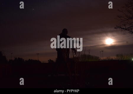 Timeline der aufgehenden Mond in der Nacht Dämmerung Himmel von einer Bronzeskulptur Silhouette in der soldatenfriedhof Reimsbach an der Saar Deutschland gesehen Stockfoto