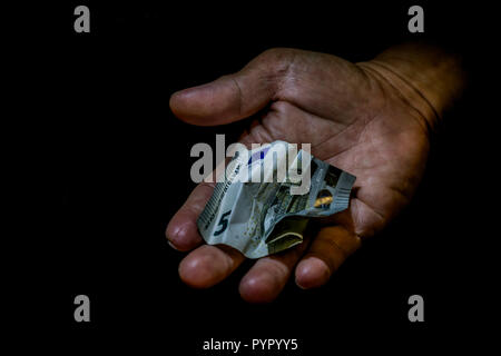 Rumpled fünf Euro Schein in der Hand einer Person isoliert auf Schwarz. Konzept der Betteln für verlassen, armen, kleinen Lohn, Spenden. Stockfoto