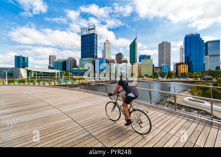 Ein Mann Radfahren über Elizabeth Quay Brücke mit Blick auf Perth City im Hintergrund. Elizabeth Street, Perth, Western Australia Stockfoto