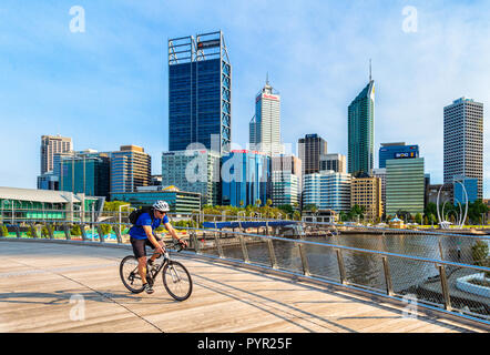 Ein Mann Radfahren über Elizabeth Quay Brücke mit Blick auf Perth City im Hintergrund. Elizabeth Street, Perth, Western Australia Stockfoto