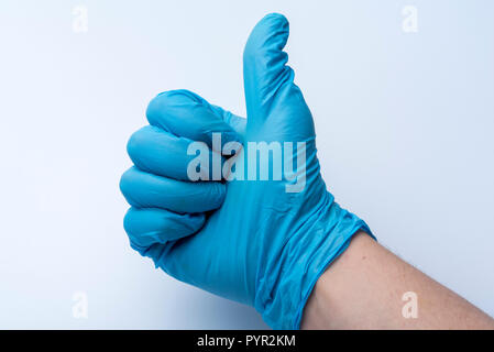 Die behandschuhte Hand zeigt der Daumen nach oben. Die blauen medizinischen Handschuhen auf die Hand des Arztes. Stockfoto