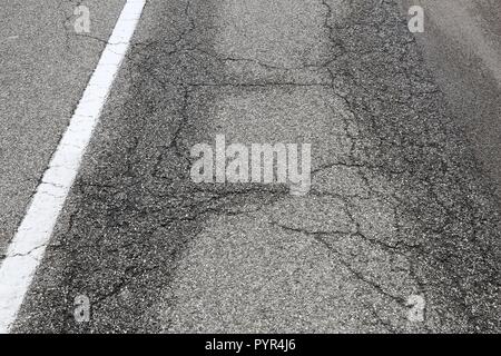 Fahrbahnoberfläche Schaden - schlechte Wartung Qualität. Asphalt Risse in Italien. Stockfoto