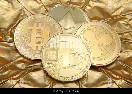 Litecoin, Welligkeit, des Astraleums & Bitcoin goldene Münzen, die cryptocurrenies gegen einen goldenen Hintergrund. Stockfoto
