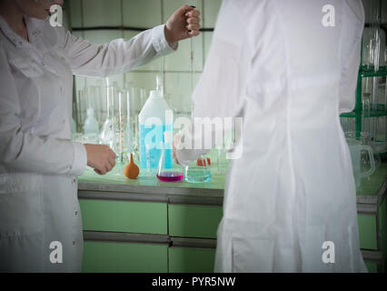 Tisch voller Chemikalien und Flaschen. Chemischen Labor. Zwei Frauen in der medizinischen Kittel Stockfoto