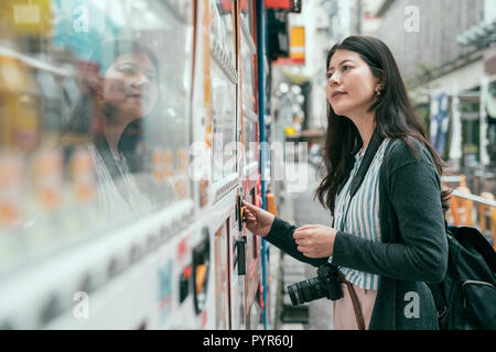 Getränkeautomat, Japan. Junge weibliche Touristen wählen Sie einen Snack oder ein Getränk am Automaten. lady Münzen in die Anbieter Maschine auf dem japanischen s Stockfoto