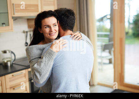 Glückliche Frau in der Umarmung des Freundes zu Hause Stockfoto