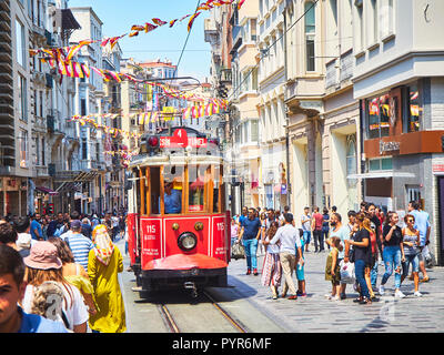 Eine Straßenbahn Überqueren der belebten Istiklal-Straße, geschmückt mit Wimpel der Galatasaray Sports Club. Beyoglu, Türkei. Stockfoto