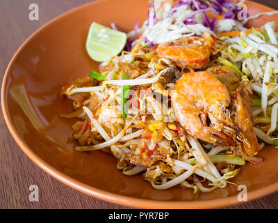 Thai gebratene Nudeln mit Garnelen und Gemüse, Pad Thai auf einem Holztisch Stockfoto