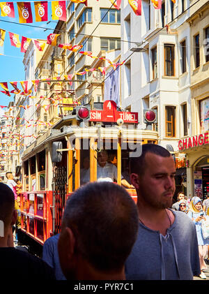 Eine Straßenbahn Überqueren der belebten Istiklal-Straße, geschmückt mit Wimpel der Galatasaray Sports Club. Beyoglu. Istanbul, Türkei. Stockfoto