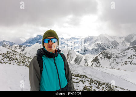 Portrait männlichen Bergsteiger in Snowy Mountains, mit einem Rucksack Stockfoto