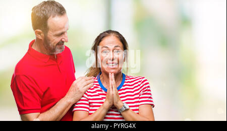 Mittleres Alter spanischer Paar in Liebe über isolierte Hintergrund mit Händen gemeinsam beten um Vergebung bat lächelnd zuversichtlich. Stockfoto