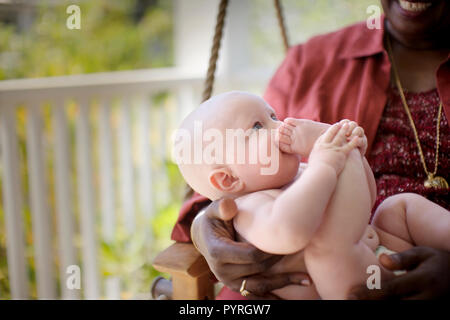 Smiling baby aloft von seiner Großmutter gehalten wird. Stockfoto