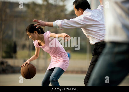 Junge erwachsene Frau basketball Bezahlen mit Ihrem mittleren - Erwachsene Geschäftsmann Vater,=. Stockfoto