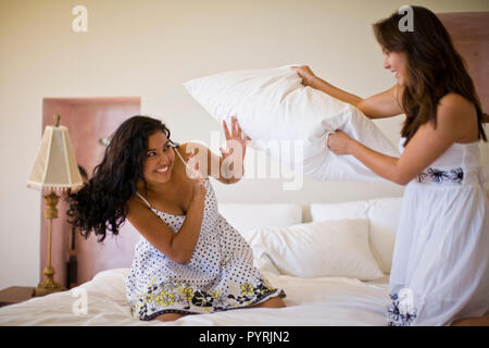 Junge Erwachsene Mädchen Kissen kämpfen auf einem Bett. Stockfoto