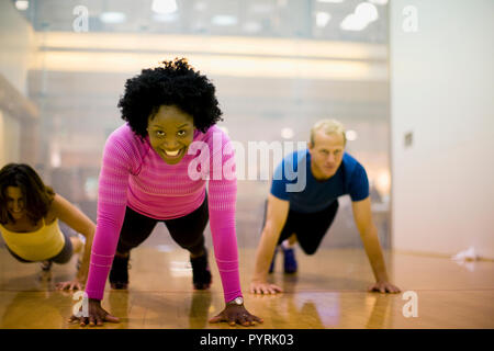 Porträt eines lächelnden jungen Frau tun, drücken Sie die USV in einem Fitnessstudio. Stockfoto