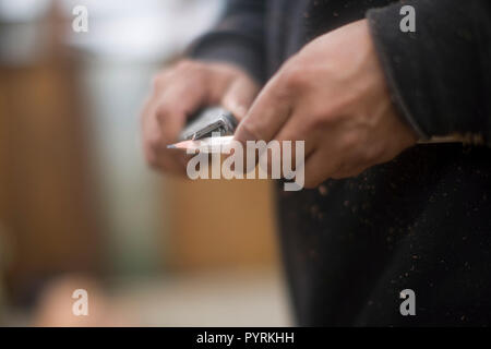 Nahaufnahmen der Hände des Menschen schärfen ein Bleistift mit einem Messer Stockfoto