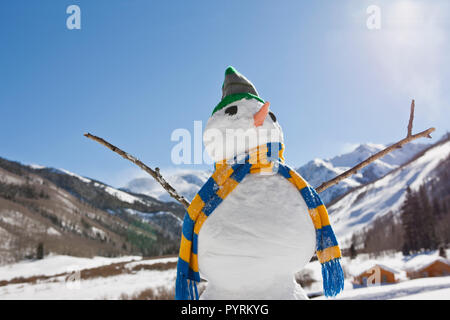 Schneemann tragen s gestreiften Schal eine Strickmütze in eine winterliche Landschaft. Stockfoto