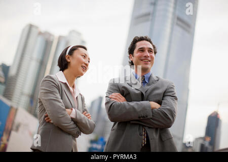 Zwei lächelnde zuversichtlich Geschäftsleute stehen mit ihren verschränkten Armen. Stockfoto