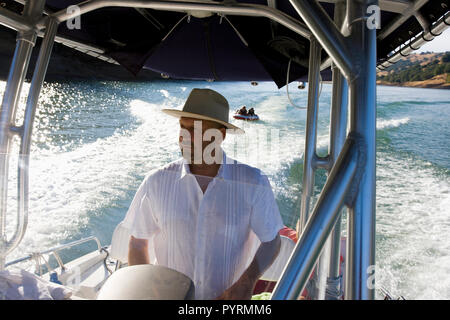 Reifer Mann mit Hut beim Lenken ein Boot auf einem See. Stockfoto