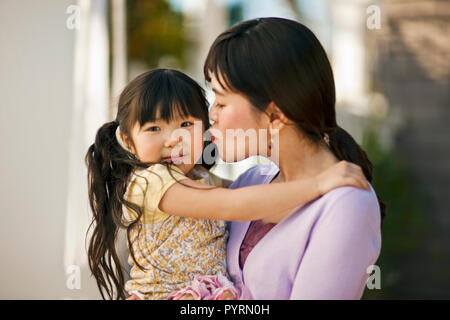 Mutter küssen ihre Tochter auf die Wange. Stockfoto