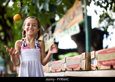 Kleines Mädchen jonglieren Obst. Stockfoto