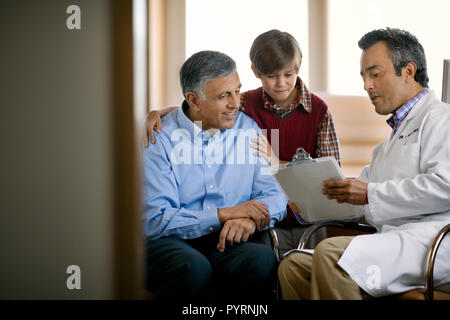 Erwachsene im mittleren Alter Arzt Rücksprache mit einem Jungen und seinem Vater. Stockfoto