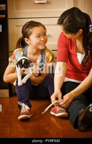 Mutter helfen, ihre Tochter ihren Schnürsenkel binden. Stockfoto