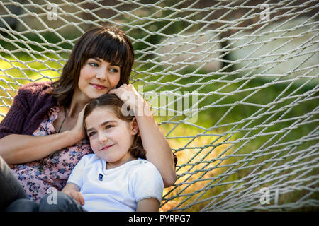 Mutter und Tochter in einer Hängematte sitzen zusammen. Stockfoto