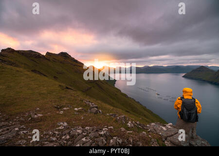 Wanderer dunkles auf Felsen sieht sich die Fjorde, Funningur, Eysturoy Island, Färöer, Dänemark Stockfoto