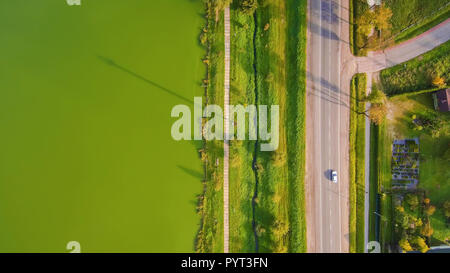 Luftaufnahme von Drone: Unterwegs mit einem Auto entlang unter grünen See. Stockfoto
