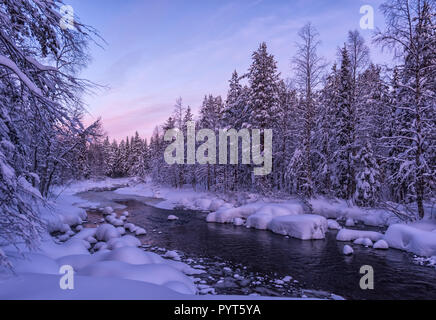 Atemberaubende winter Lappland Landschaft mit wunderschönen Sonnenuntergang, nicht gefrorenen Fluss und verschneiten Wald. Unberührte weiße Schnee am Flussufer. Fantastisches Eis ein Stockfoto