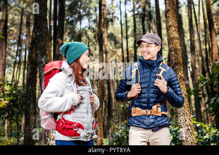 Jungen asiatischen Wanderer mit Rucksack stehen und einander im Wald Stockfoto