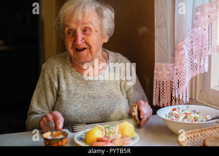 Ältere Frau Essen am Tisch zu Hause. Stockfoto