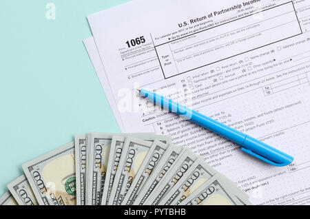 1065 Steuerformular liegt in der Nähe von Hundert-euro-Scheine und blauen Stift auf einem hellblauen Hintergrund. Uns parentship Einkommen. Stockfoto