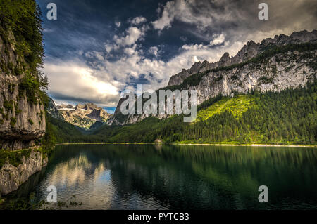 Farbenfrohe Sommer Szene der seitlichen vorderen Gosausee mit Wald- und felsigen Hügeln im Hintergrund Stockfoto