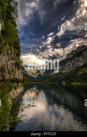 Farbenfrohe Sommer Szene der seitlichen vorderen Gosausee mit Wald- und felsigen Hügeln im Hintergrund Stockfoto