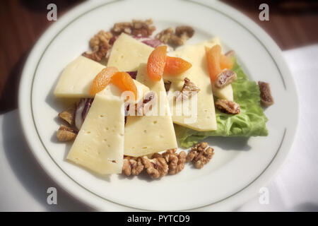 Nahaufnahme Teller mit Käse und getrockneten Früchten mit Walnuss auf Frühstückstisch Stockfoto