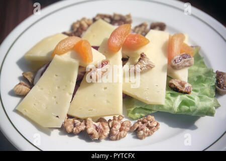 Nahaufnahme Teller mit Käse und getrockneten Früchten mit Walnuss auf Frühstückstisch Stockfoto