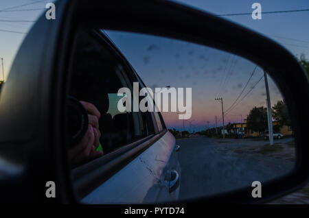 Straße von der Innenseite eines Autos und die Reflexion der Rückspiegel des Autos. Road Trip bei Sonnenuntergang, Sonnenuntergang aus dem Inneren des Autos. Stockfoto